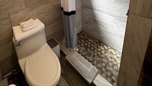 A bathroom with a toilet, shower, and tiled floor.