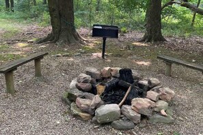 Ein Lagerfeuer, umgeben von Steinen, mit einem Wegweiser im Hintergrund.