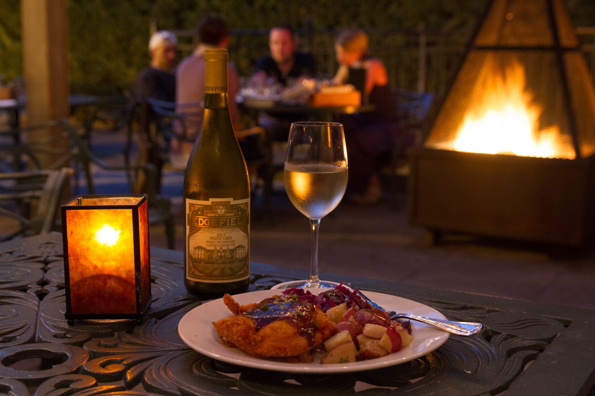 A dining table with a candle, a bottle of wine, and a glass of wine.