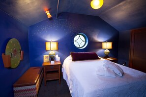 A bedroom with a bed, two bedside lamps, a nightstand, a globe, and a wall clock.