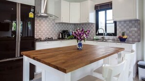 Une cuisine moderne avec des meubles blancs, un îlot central en bois et un vase de fleurs.