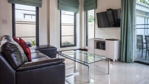 Un salon moderne avec une table basse en verre, un canapé en cuir et un téléviseur à écran plat fixé au mur.