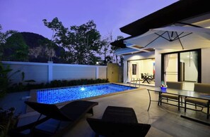Un espace piscine extérieur moderne, doté d’un coin repas et d’un espace salon abrité.
