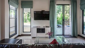 Un salon moderne avec un canapé en cuir, une table basse en verre, un téléviseur à écran plat et un système audio.