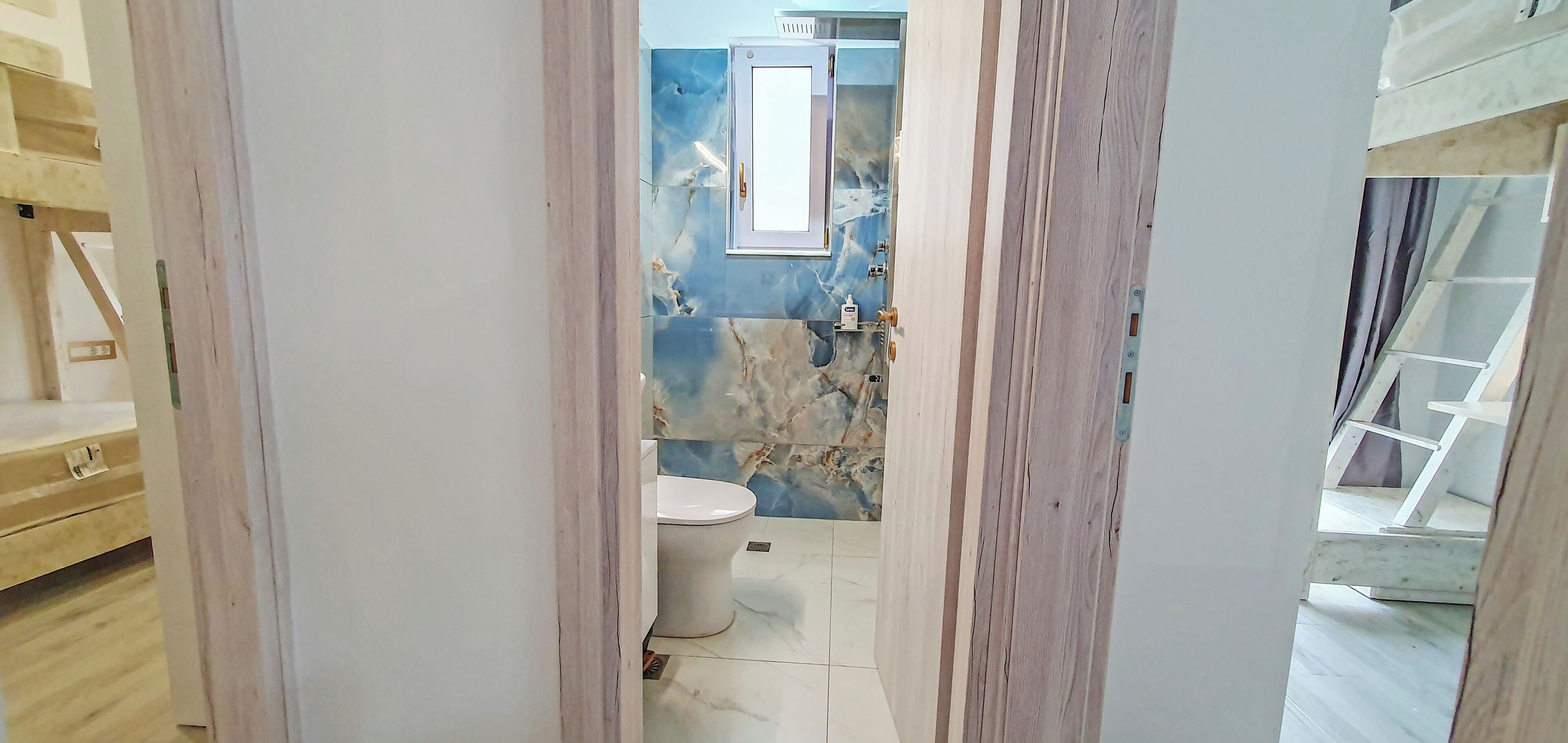 A bathroom with a toilet, a mirror, and a marble backsplash.
