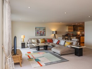 A modern living room with a sectional sofa, a coffee table, and a colorful rug.