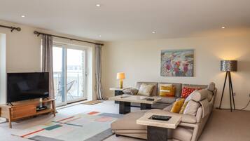A modern living room with a flat-screen TV, a sofa, a coffee table, and a floor lamp.