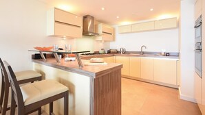 Una cocina moderna con una isla central, taburetes de bar y un horno empotrado.