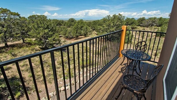 Ein Balkon mit Holzboden, Metallgeländer und einem kleinen Tisch mit Stühlen.