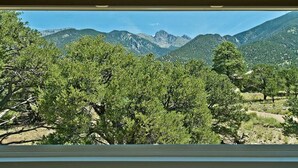 Blick aus einem Fenster auf eine gebirgige Landschaft mit dichtem Grün.