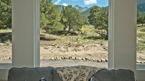 Ein Zimmer mit Blick auf eine Berglandschaft durch große Fenster.