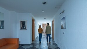 A hallway with a checkered floor, a sofa, and framed pictures on the walls. - Delta rooms (Olbia)