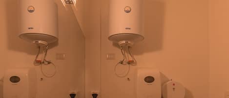 A bathroom with two wall-mounted heaters, a sink with a marble countertop, a toilet, and a towel rack.