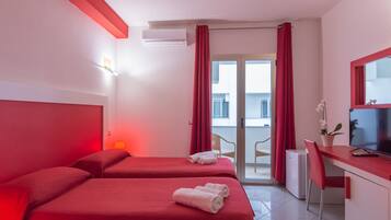 Une chambre d’hôtel avec deux lits, un bureau avec une télévision et un balcon avec des rideaux rouges.