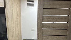 Een kleine wasruimte met een wasmachine, ventilatie en een wand van houten panelen.