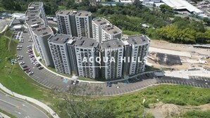 Een hoog appartementencomplex met meerdere balkons, een parkeerplaats en een aangelegde groenvoorziening.