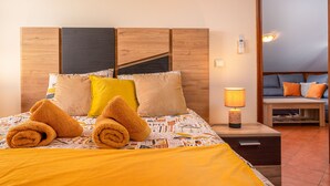 A neatly made bed with rolled towels, a bedside lamp, and a wooden headboard. - Sunset House (Arco da Calheta)