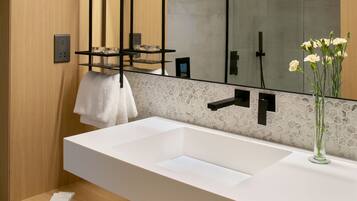 A modern bathroom with a large white sink, a mirror, and a towel rack.