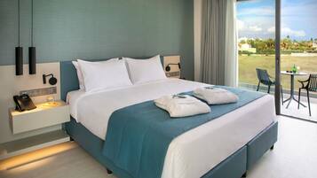 A modern hotel room with a large bed, a bedside table with a phone, and a view of the outdoors.