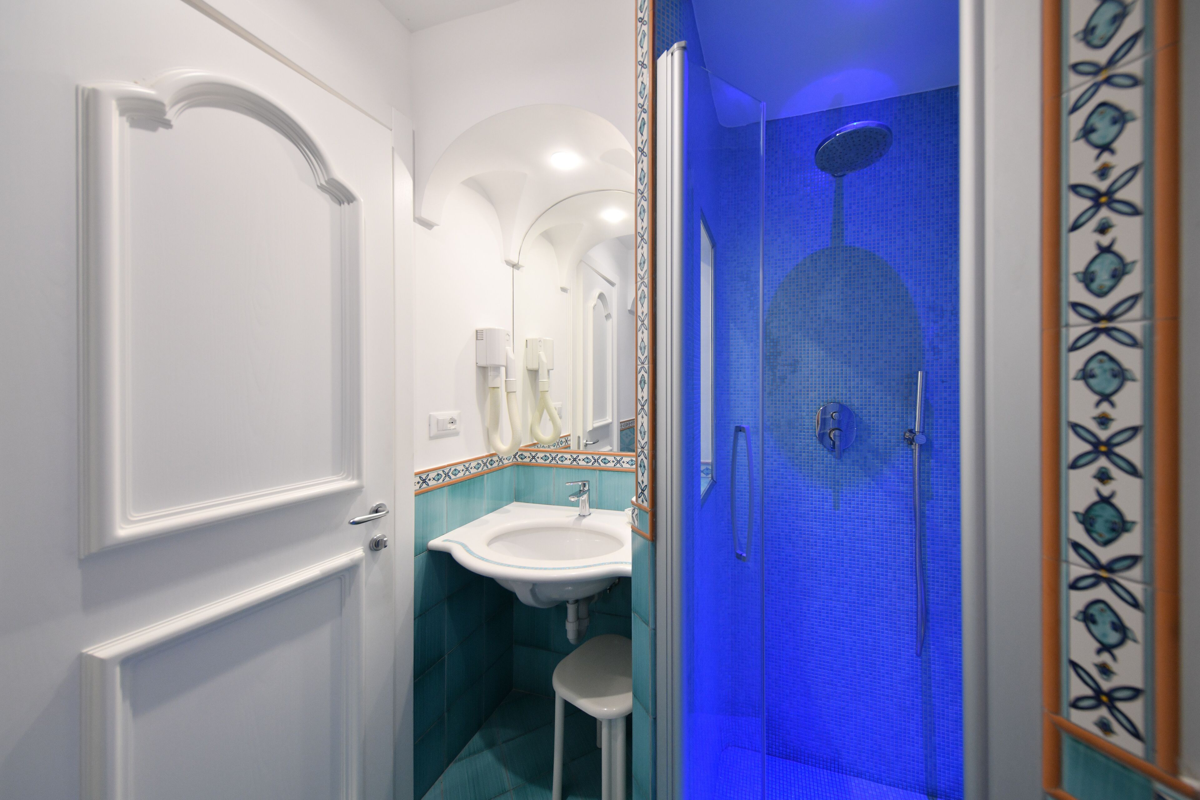 A bathroom with a white door, a sink, and a shower with blue lighting.