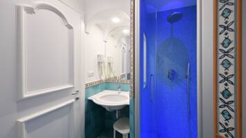Un baño con una puerta blanca, un lavamanos y una ducha con iluminación azul.