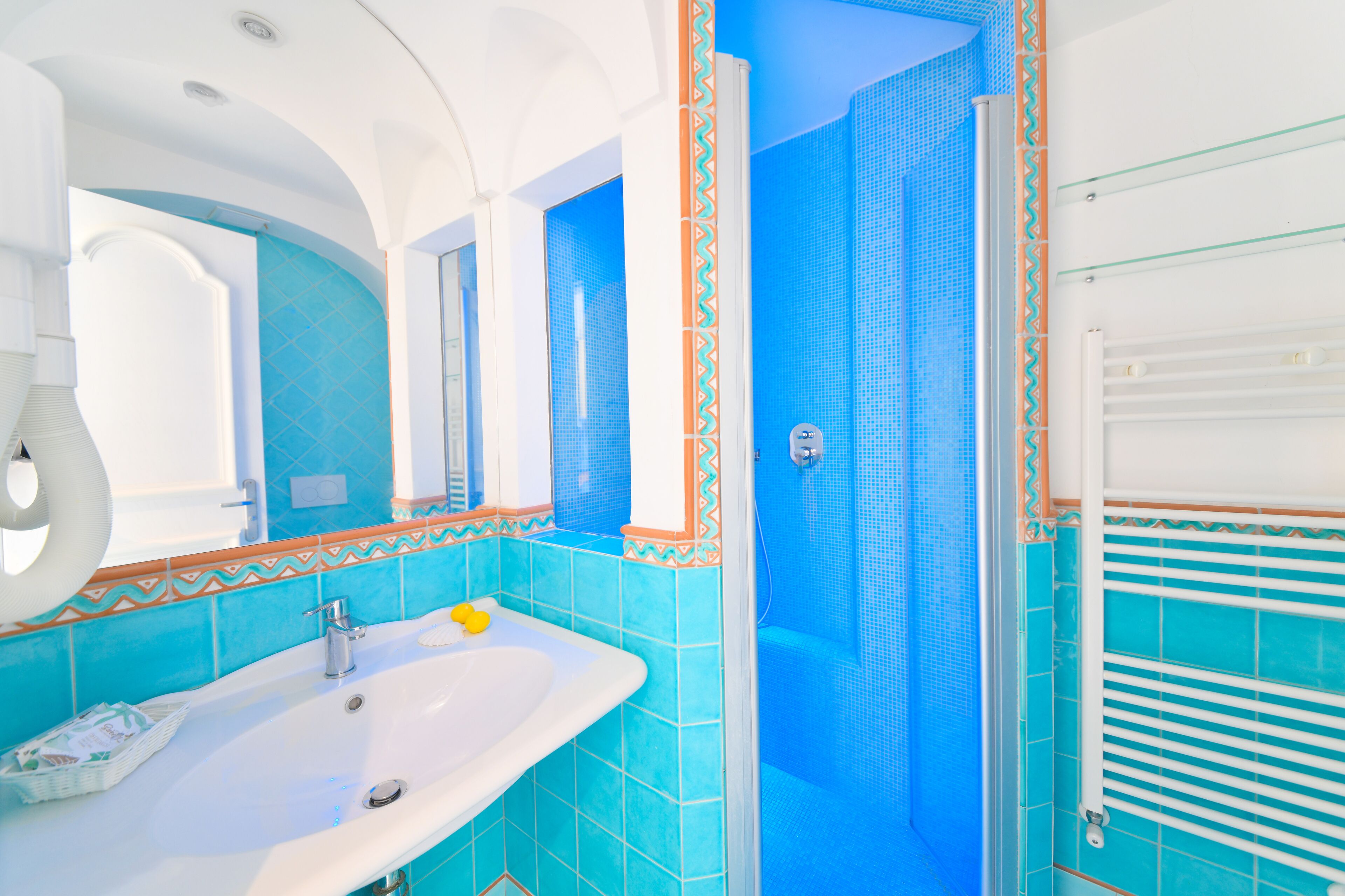 A bathroom with a white sink, blue tiles, and a shower area.