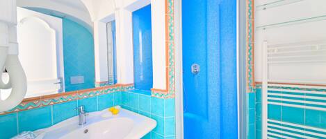 A bathroom with a white sink, blue tiles, and a shower area.