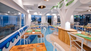 A modern restaurant with a nautical theme, featuring blue and white decor, wooden tables, and white chairs.