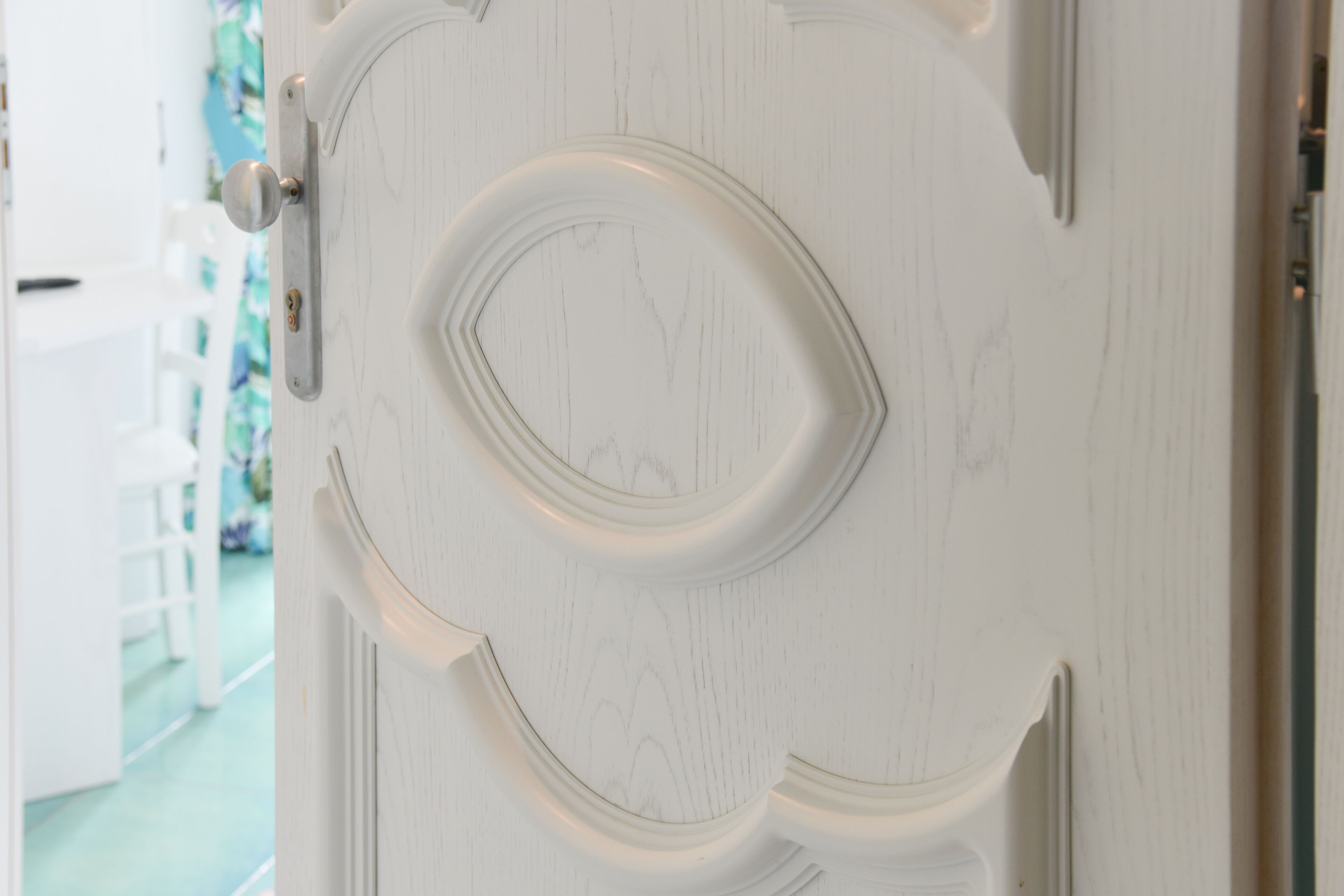 A white door with a decorative design and a round handle.