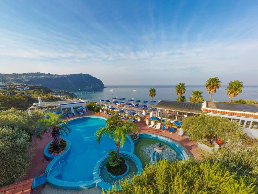 Una piscina techada, una piscina al aire libre, sombrillas