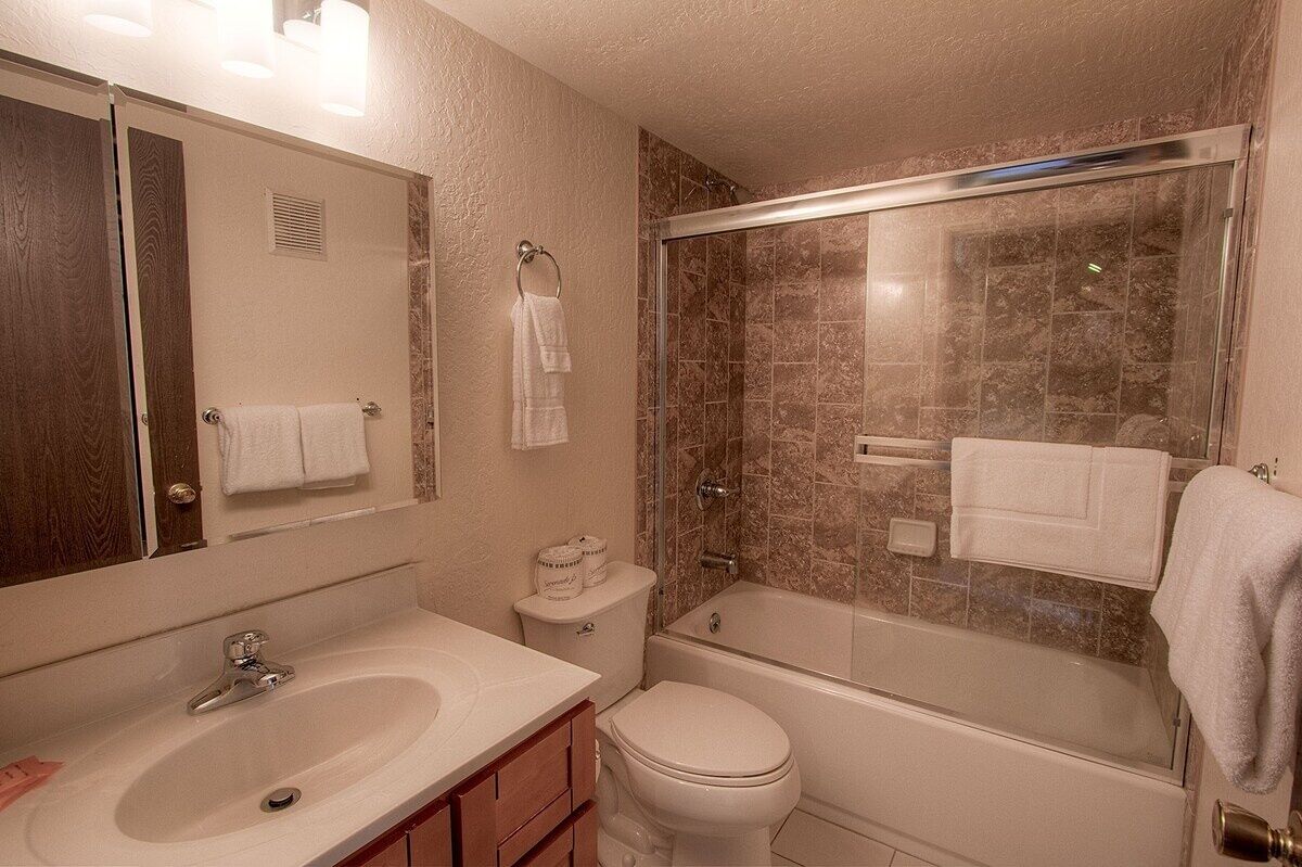 A bathroom with a sink, toilet, bathtub, and a glass-enclosed shower.