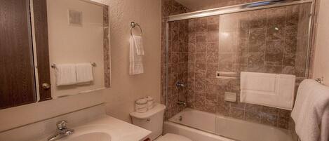 A bathroom with a sink, toilet, bathtub, and a glass-enclosed shower.