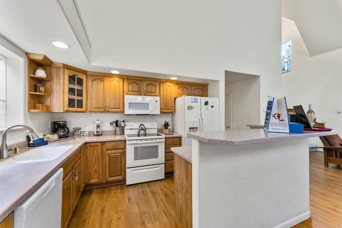 A modern kitchen with wooden cabinets, white appliances, and a breakfast bar.