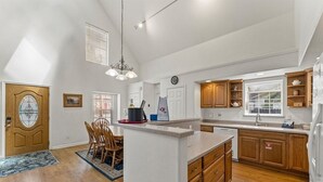 A spacious kitchen with wooden cabinets, a central island, and a dining area with chairs. - Sierra Mountain Lodge 3 Bedroom Home by RedAwning (South Lake Tahoe)