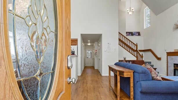 A spacious living area with a wooden floor, a blue sofa, a wooden coffee table, and a staircase leading to another level. - Sierra Mountain Lodge 3 Bedroom Home by RedAwning (South Lake Tahoe)