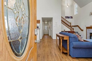 Un vaste espace de vie doté d’un plancher en bois, d’un canapé bleu, d’une table basse en bois et d’un escalier menant à un autre niveau.