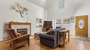 A living room with a fireplace, a sofa, a television, and a wooden coffee table. - Sierra Mountain Lodge 3 Bedroom Home by RedAwning (South Lake Tahoe)