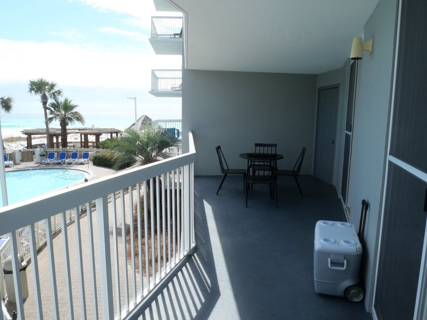 Een balkon met een zwembad, stoelen en een tafel.