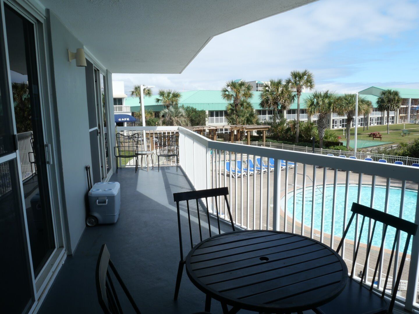 Un balcon donnant sur une piscine, avec des chaises et une table.