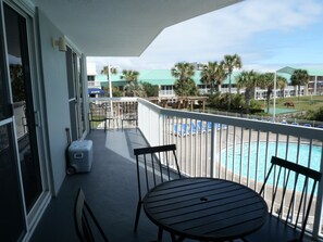 A balcony with a view of a pool, chairs, and a table. - Pelican Beach 0212 2 Bedroom Condo by Pelican Beach Management (Destin)