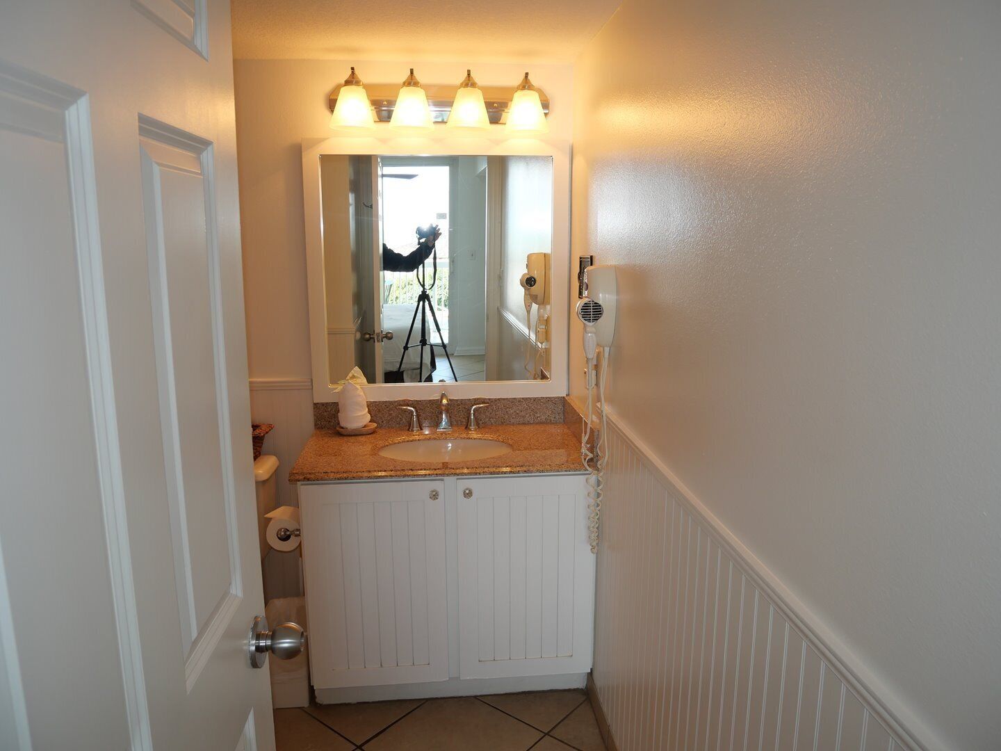 A bathroom with a double sink, vanity, and a mirror with lights.