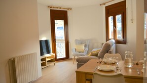 A dining area with a table set for two, a television on a stand, and a window with a view of the outdoors. - Apartment with views and central in Esterri (Esterri d'Àneu)