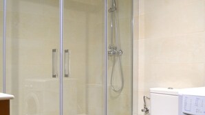A modern bathroom with a glass-enclosed shower, a toilet, and a washing machine. - Apartment with views and central in Esterri (Esterri d'Àneu)