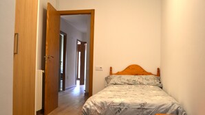 A bedroom with a wooden bed, a nightstand, and a door leading to another room. - Apartment with views and central in Esterri (Esterri d'Àneu)