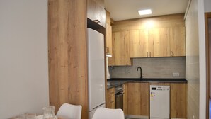 A modern kitchen with wooden cabinets, a dishwasher, and a dining area with a table set for four. - Apartment with views and central in Esterri (Esterri d'Àneu)