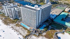 Ein Hochhaus-Hotel mit zahlreichen Balkonen, einem Schwimmbad und einer Strandanlage.