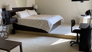 Un dormitorio con cama, mesitas de noche, escritorio, silla y televisor.