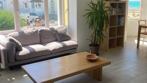 A living room with a sofa, a coffee table, a bookshelf, and a potted plant. - Duplex 5 persons seaside. (Wissant)