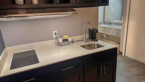 A kitchen with a stainless steel countertop, a double sink, a built-in oven, and a coffee maker. - Suburban Studios Montpelier (Montpelier)