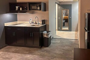 A modern kitchen with dark cabinets, a stainless steel sink, and a microwave above the counter. - Suburban Studios Montpelier (Montpelier)